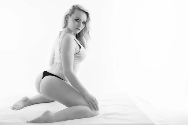 Mladá blond žena klečí na posteli — Stock fotografie