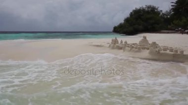 Dalgalar küçük sandcastle ile bir plajda