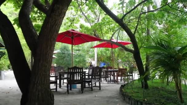 Кафе на острове мебель с красным зонтиком — стоковое видео