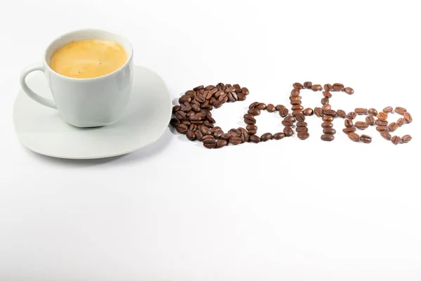 White cup with coffee on a white background and coffee beans — 스톡 사진