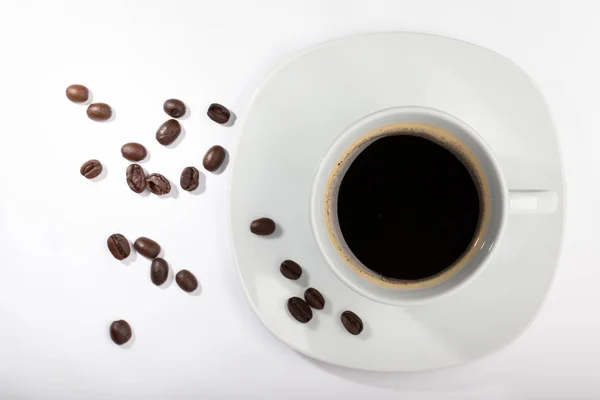 White cup with coffee on a white background and coffee beans — 스톡 사진