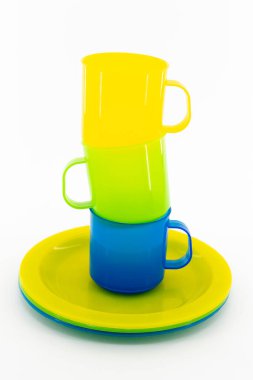 Beyaz arka planda üç renkli kupa ve üç renkli çay tabağı.