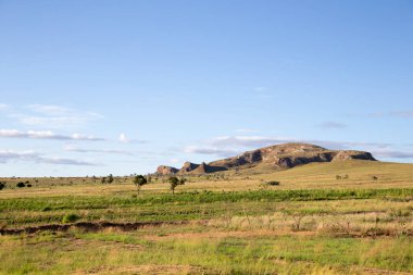 Dağlar bitkilerle kaplı ve mavi gökyüzü küçük bulutlarla kaplı.