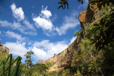 Dağlar bitkilerle kaplı ve mavi gökyüzü küçük bulutlarla kaplı.