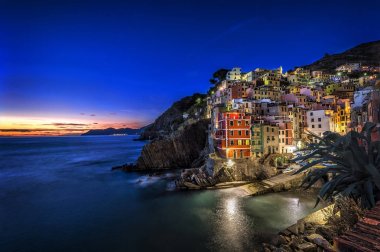 Riomaggiore fisherman village at sunset. Riomaggiore is one of five famous colorful villages of Cinque Terre in Italy, suspended between sea and land on sheer cliffs. clipart