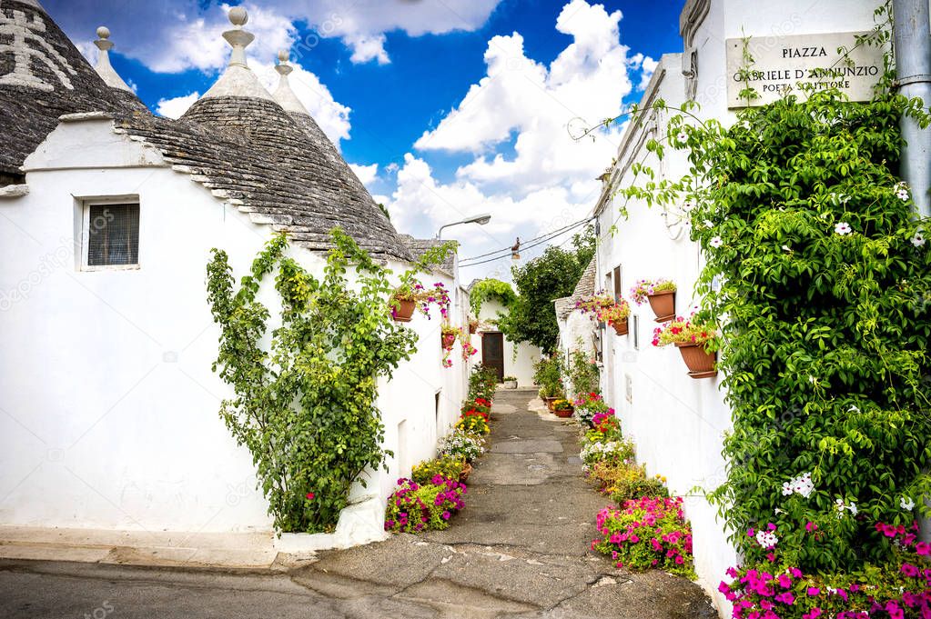 Alberobello, Italy. Beautiful town of Alberobello with trulli houses among green plants and flowers, main touristic district. Unesco world heritage on Puglia, southern Italy