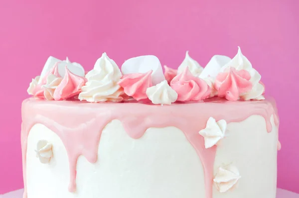 Birthday pink cake for girl, decorated with marshmallow, meringue cookies on a pink background.