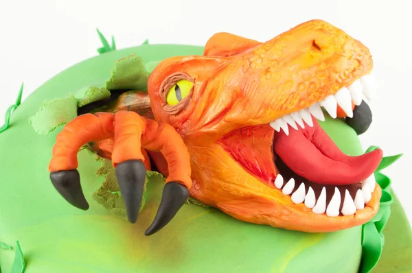 Art cake with orange dinosaur, decorated with green leaves. Gift for the boy. Picture for a menu or a confectionery catalog.