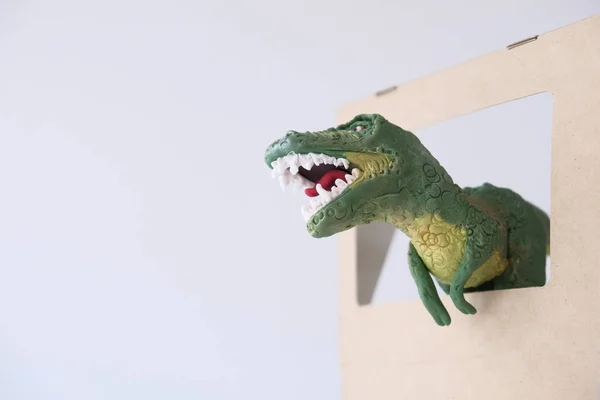 3d movie, cinema or entertainment concept. Miniature dinosaur figure coming out of the screen on a white background.