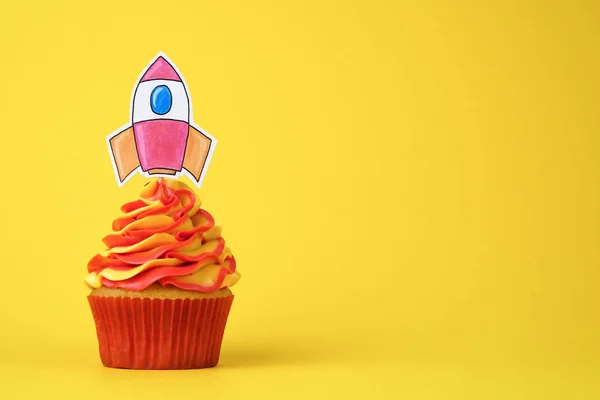 Cupcake with rocket. Startup concept. Dessert decorated red and yellow whipped cream on yellow background.