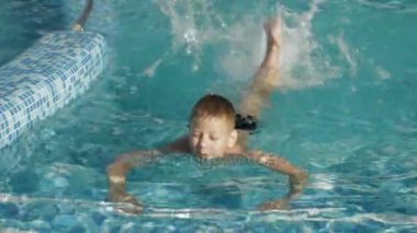 Havuzda ve bacakları su sıçramasına tekme çocuk