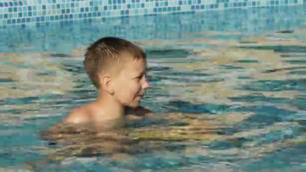 Niño jugando en la piscina con pistola de agua — Vídeo de stock