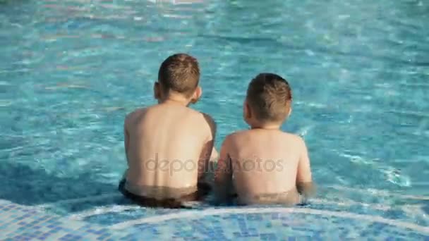 Vista trasera de los niños pequeños relajándose en la piscina — Vídeo de stock