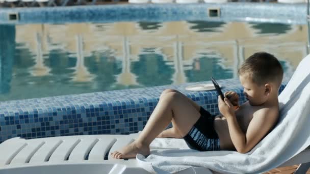 Menino descansando perto da piscina — Vídeo de Stock