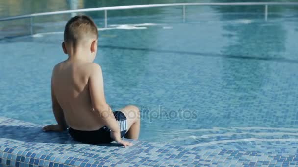 Bakifrån av liten pojke avkopplande nära poolen — Stockvideo