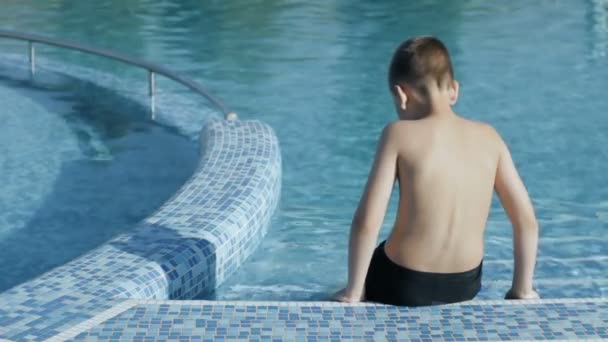 Rückansicht eines Jungen, der sich am Pool entspannt — Stockvideo