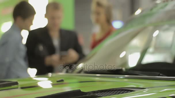 Verkäufer und Käufer in der Autoshow. Mann und Mädchen mit einem Verkäufer auf einer Autoshow — Stockvideo