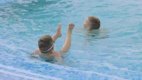 Αγόρι σε ποτήρια για κολύμπι κολυμπά στην πισίνα με τον αδελφό — Αρχείο Βίντεο