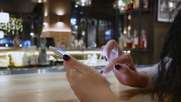 Ferme les mains. Fille en ligne sur smartphone au restaurant 