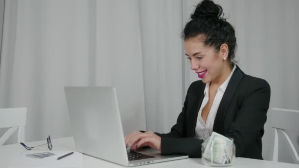 Femme retire des dollars américains de son ordinateur portable et des clins d'oeil. Concept d'abondance — Video