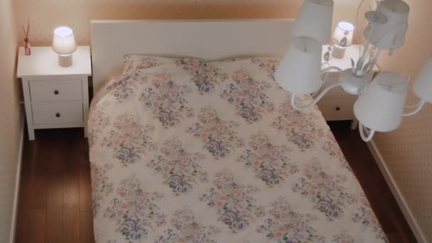 Blij krullend jonge vrouw valt op het bed in kamer — Stockvideo