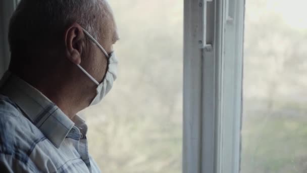 Starší muž se podívá z okna — Stock video