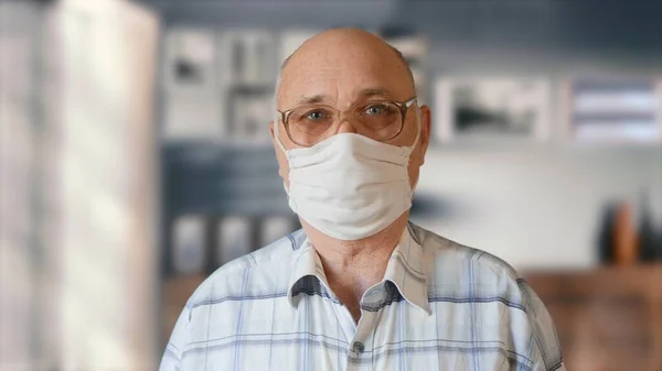 Hombre anciano en mascarilla protectora casera hecha a mano en interiores Imagen De Stock