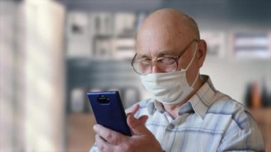 Yaşlı adam evdeki akıllı telefondan haberleri okuyor.