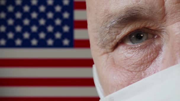 Demi-visage d'un homme âgé en masque de protection USA drapeau arrière-plan — Video