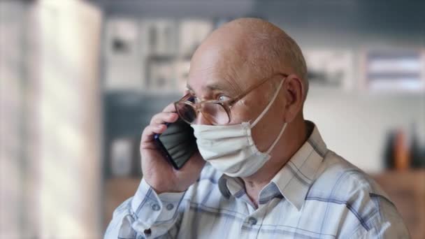 Oude man spreekt aan de telefoon thuis — Stockvideo