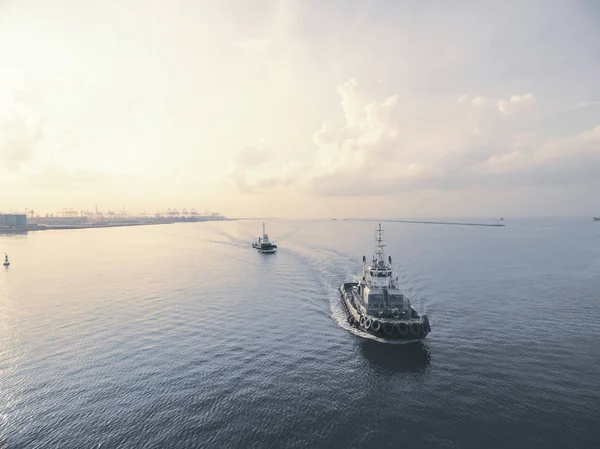 Dos remolcadores corriendo en el mar al atardecer . Imagen De Stock