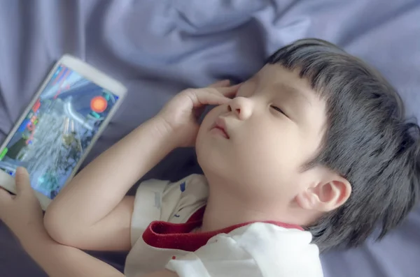 Asian children playing mobile phone have eye pain on the bed . — Stock Photo, Image