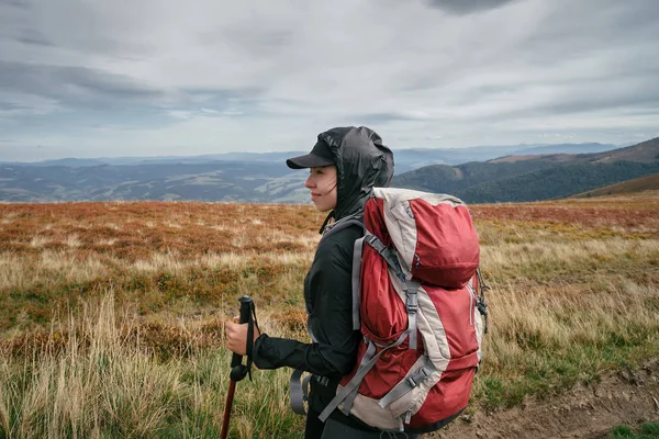 Hiking woman in mountains, inspirational landscape. Motivated hiker with backpack looking at mountain view