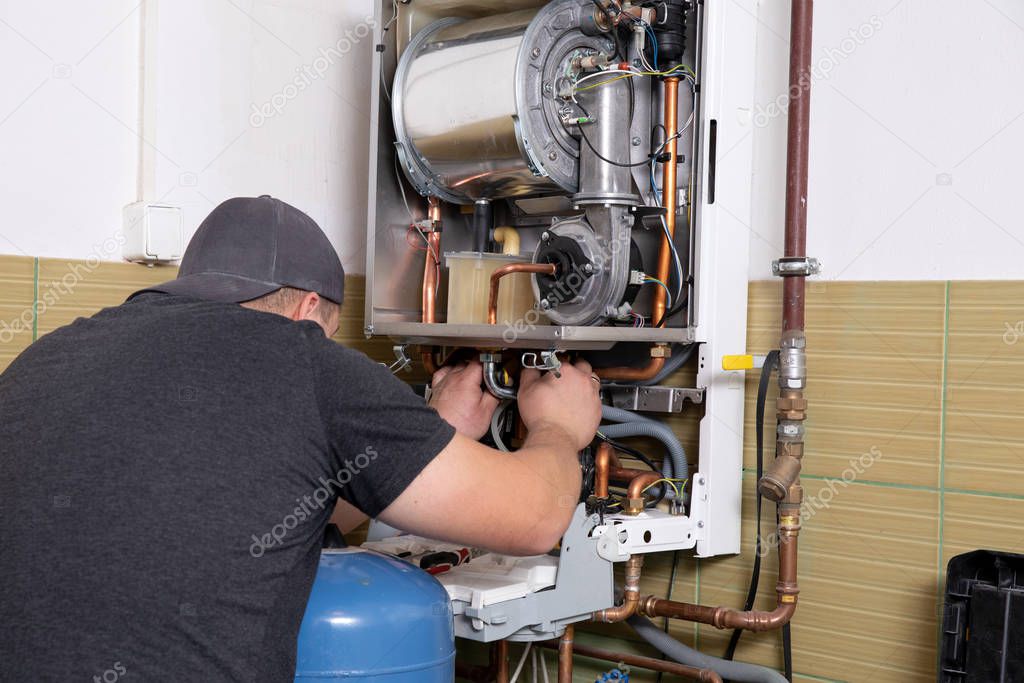plumber fixing central heating system, Worker servicing a gas boiler