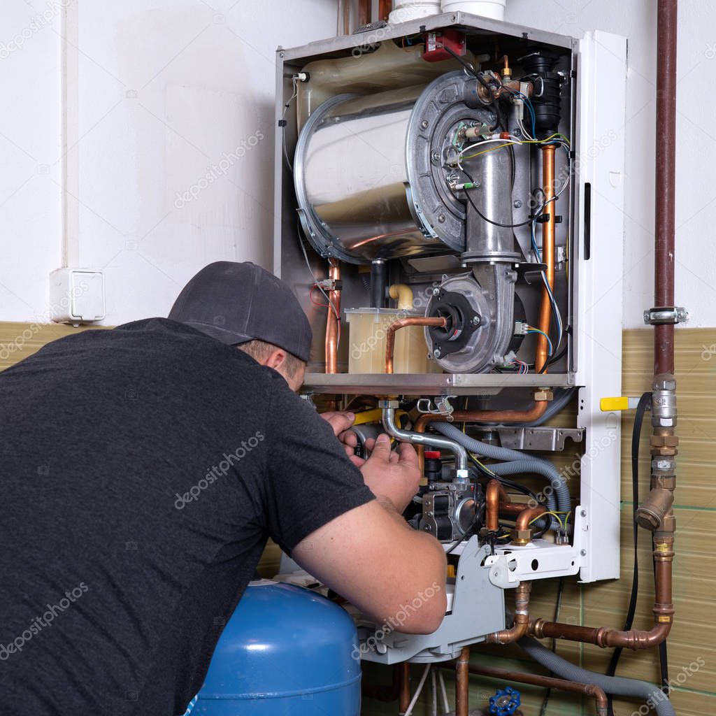 plumber fixing central heating system, Worker servicing a gas boiler