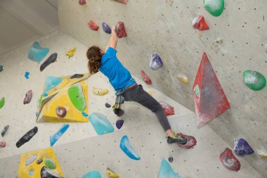 Boy on climbing wall, Bouldersport , boy climbing a rock wall indoor