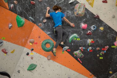 Boy on climbing wall, Bouldersport , boy climbing a rock wall indoor