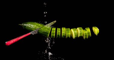 cucumber with splashing water or explosion flying in the air isolated on black background