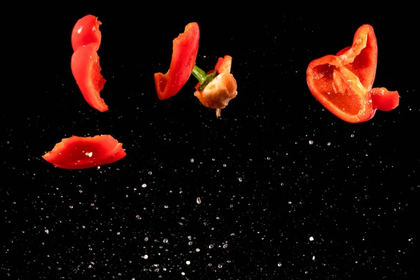 Slices of red peppers falling into the water — Stok fotoğraf