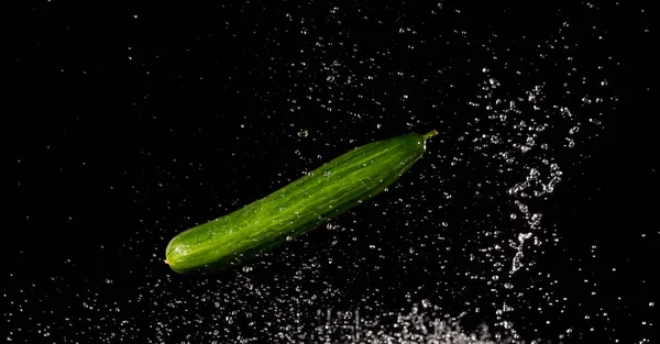Cucumber with splashing water or explosion flying in the air isolated on black background — Stok fotoğraf