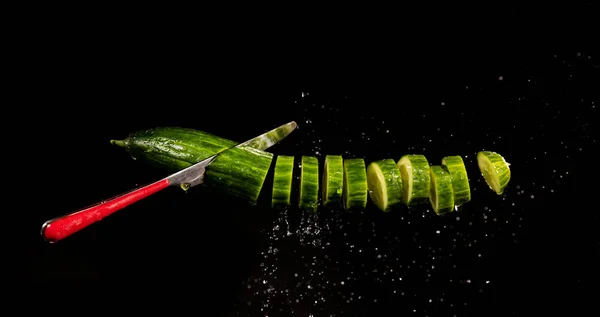 Cucumber with splashing water or explosion flying in the air isolated on black background — ストック写真