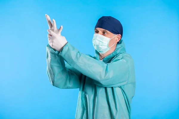 Medical worker in a mask for protection against viruses puts on gloves