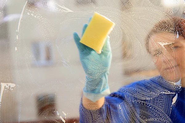 housekeeping: cleaning the windows, Window cleaner using a squeegee, sponge and soap suds to wash a window