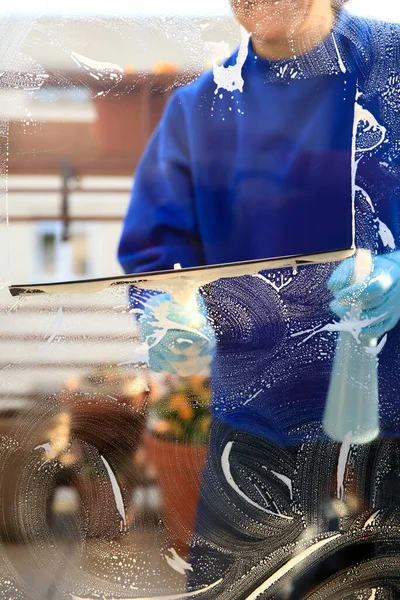 housekeeping: cleaning the windows, Window cleaner using a squeegee, sponge and soap suds to wash a window
