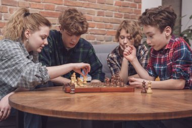 Arkadaşlık, iletişim ve insanlar - bir grup mutlu genç arkadaş evde dinleniyor, oyunlar oynuyorlar, konuşuyorlar, televizyon izliyorlar.