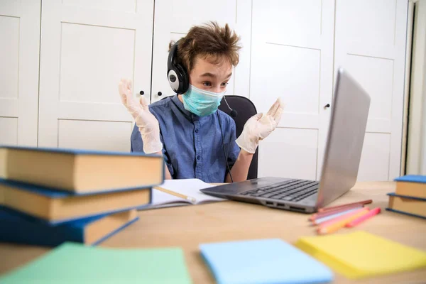 Distance learning online education. schoolboy in medical mask studying at home, coronavirus quarantine