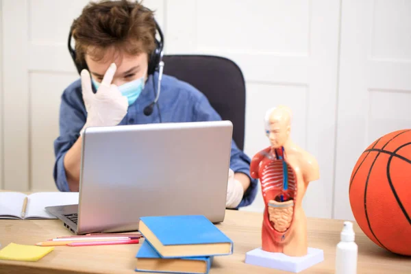 Distance learning online education. schoolboy in medical mask studying at home, coronavirus quarantine
