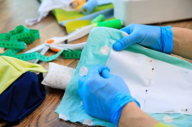 Kumaş pamuktan el yapımı moda maske. Ev yapımı tekstil yüz, burun ve ağız maskesi virüse karşı. Bir covid-19 salgını sırasında evde koruyucu yüz maskeleri dikmek