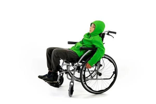 白い背景の車椅子の男の子が 男の子は白い背景の車椅子に座っている 障害のある病院の患者 — ストック写真