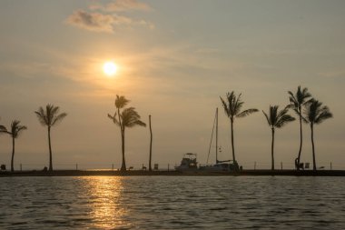 Hawaii 'nin büyük adasındaki Waikoloa Sahili' ndeki Anaehoomalu Sahili 'ndeki suya yansıyan palmiye ağaçları ve botlar.